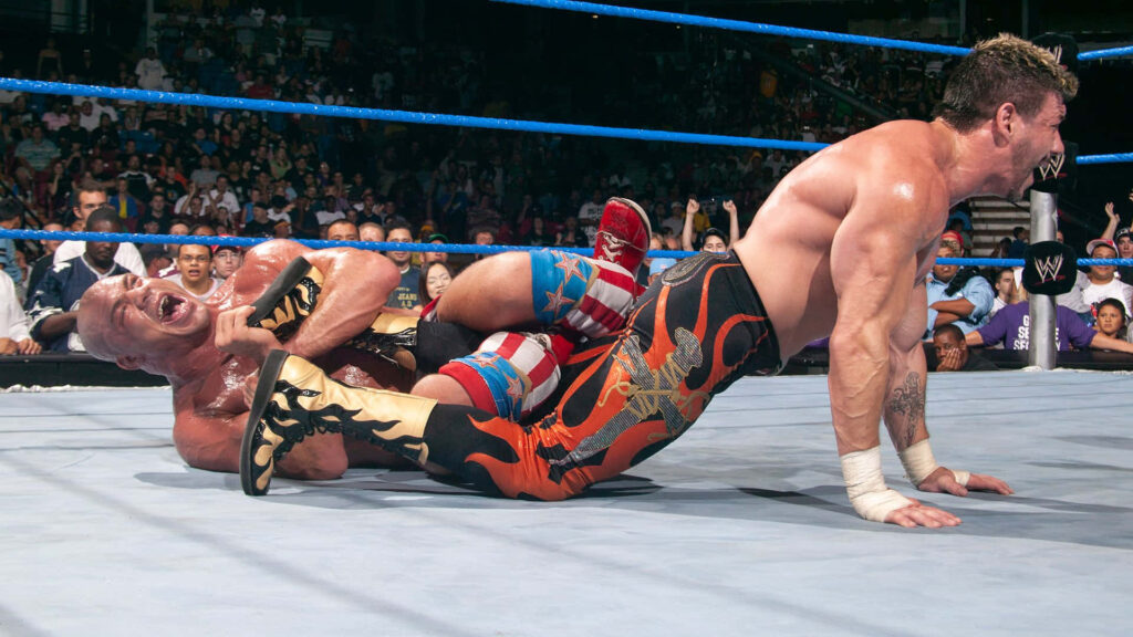 Eddie Guerrero and Kurt Angle wrestling mid-move in vibrant arena showcasing intense action Wallpaper