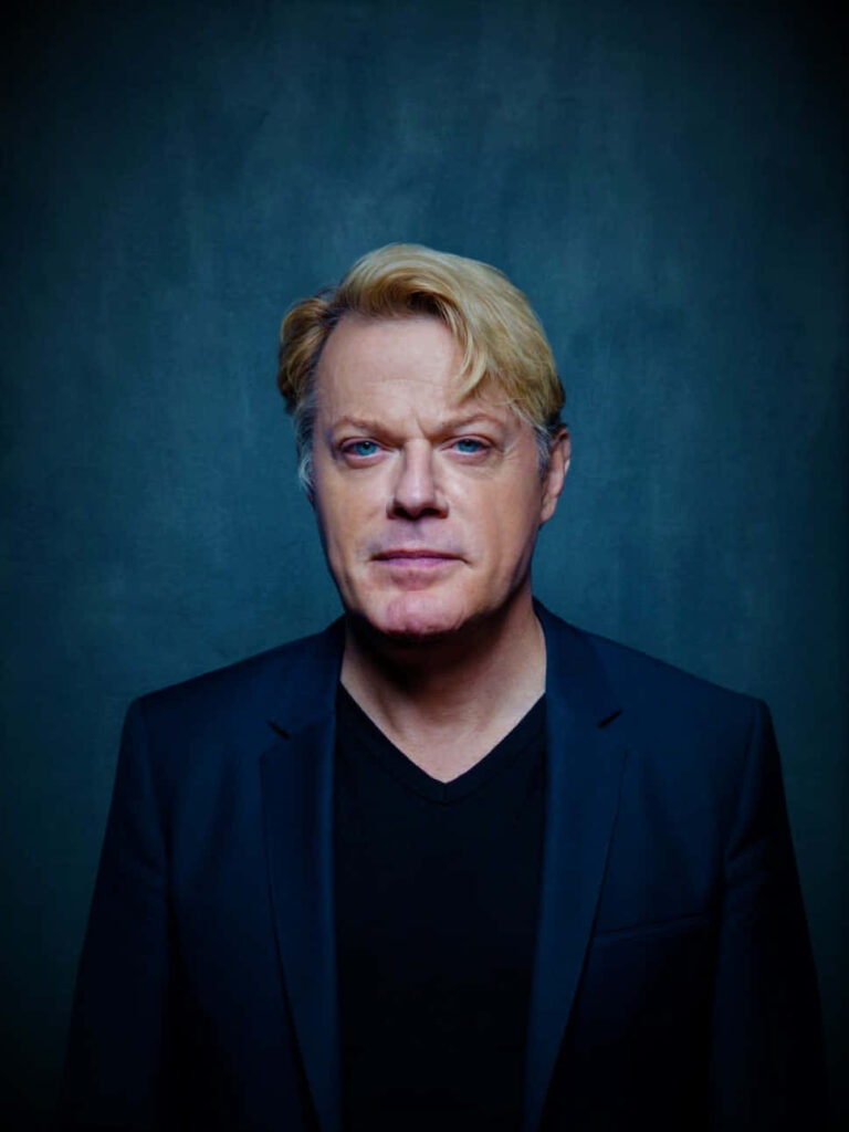Eddie Izzard portrait wallpaper deep blue textured background confident expression style
