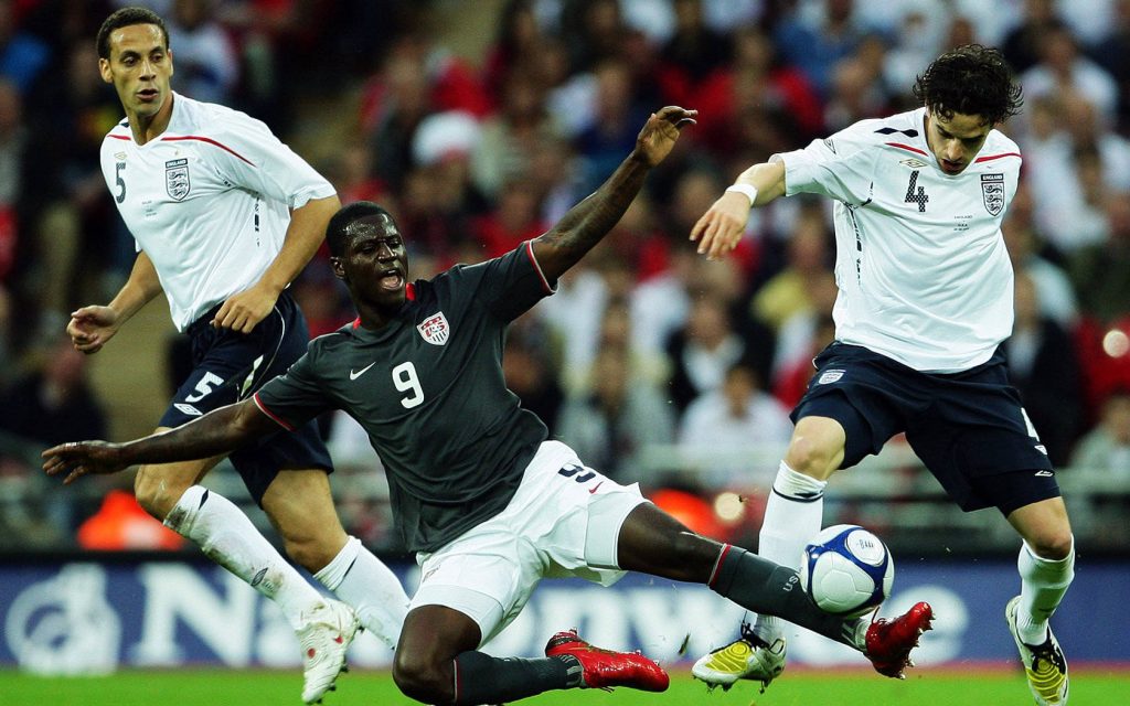 Eddie Johnson fights for ball against Rio Ferdinand and Steven Gerrard in intense soccer match Wallpaper