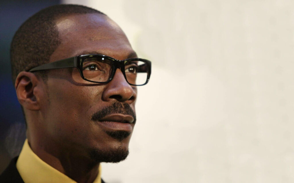 Close-up side profile of Eddie Murphy with glasses warm lighting and thoughtful expression wallpaper