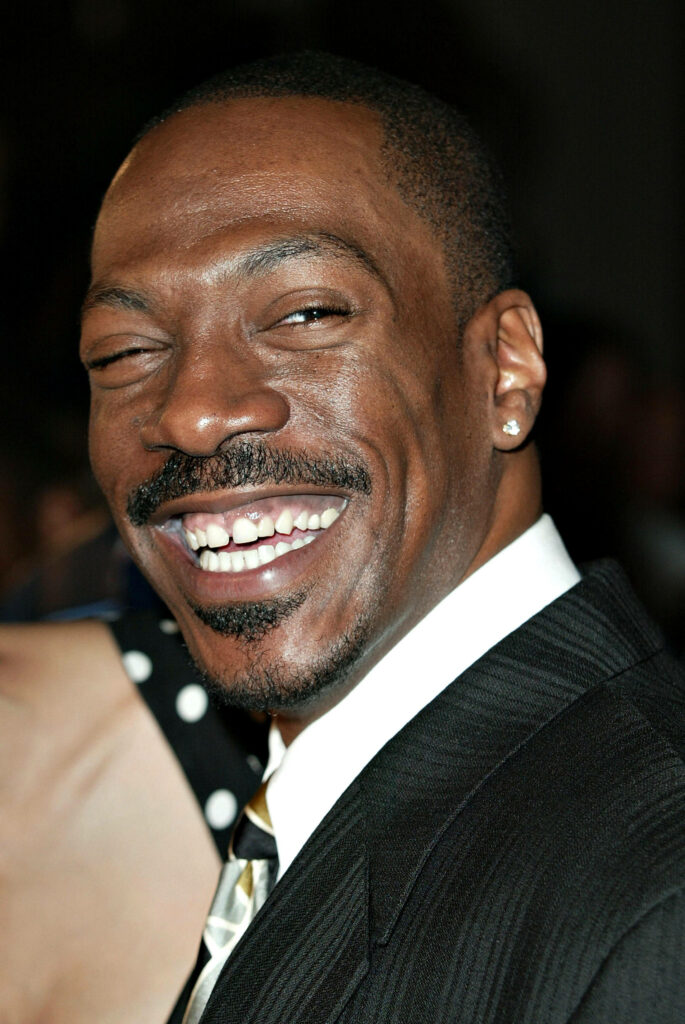 Eddie Murphy close-up portrait with iconic smile vibrant expression formal attire wallpaper background