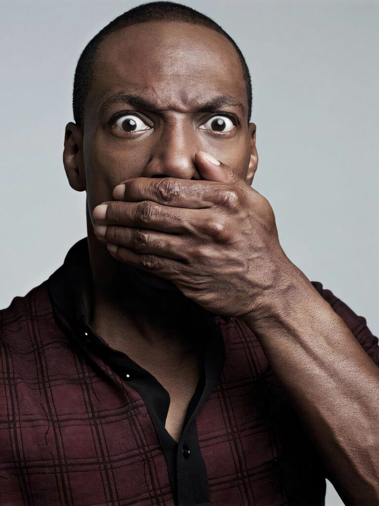 Eddie Murphy surprised expression hand over mouth plaid shirt soft gray background wallpaper