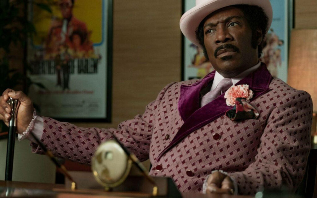 Eddie Murphy as Rudy Ray Moore vibrant 1970s wallpaper pink purple suit retro style background