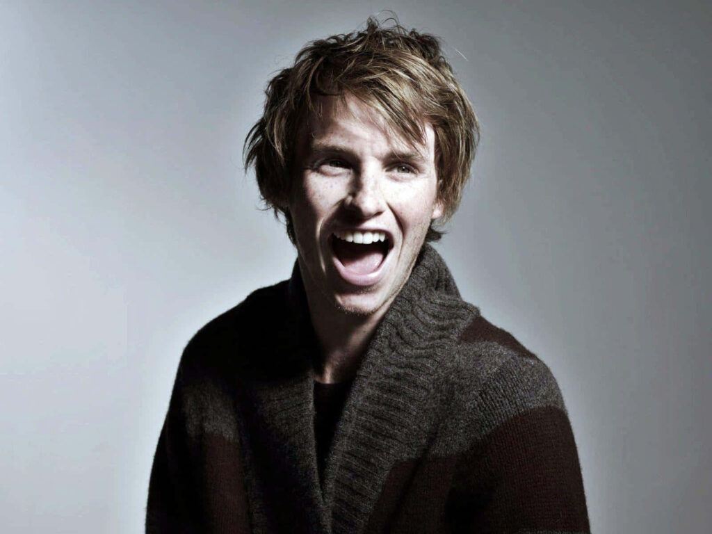 Eddie Redmayne joyful candid portrait in cozy knit sweater with soft gradient background wallpaper