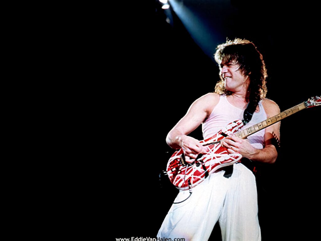Eddie Van Halen playing iconic red white striped guitar on stage in white tank top classic rock Wallpaper