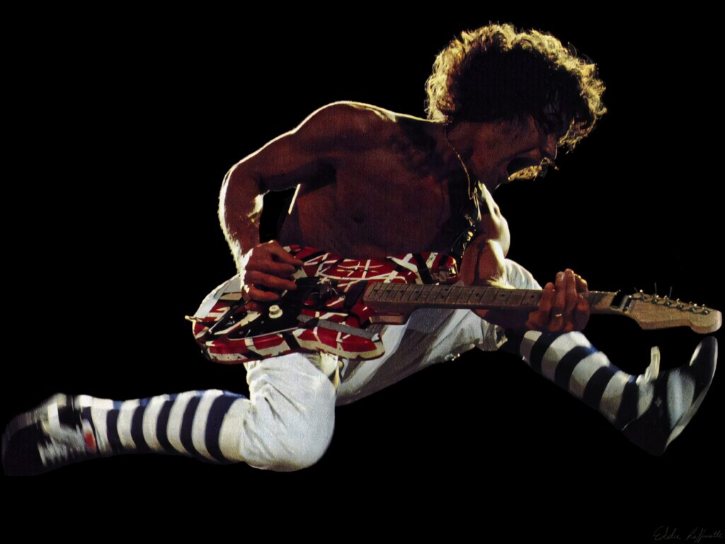 Eddie Van Halen mid-air jump playing red-striped guitar showcasing legendary rock energy Wallpaper