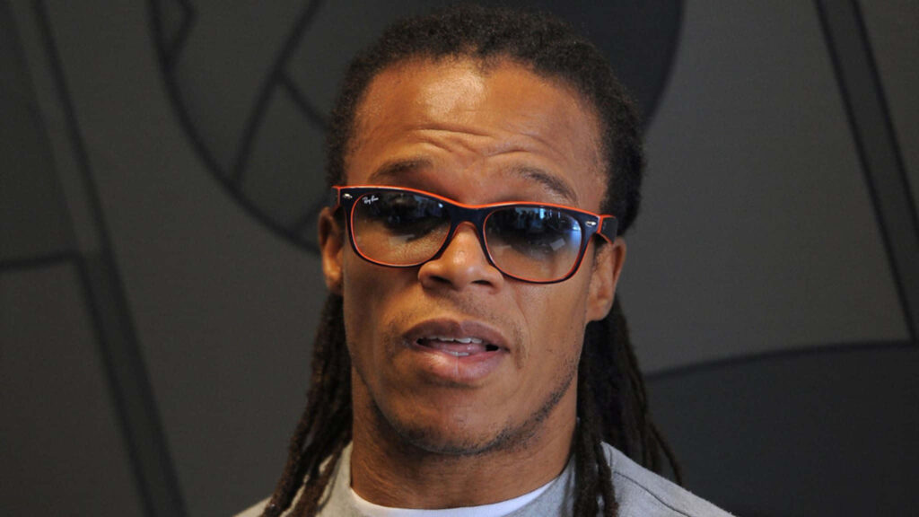 Close-up of Edgar Davids with dreadlocks and sports glasses on minimalist wallpaper background