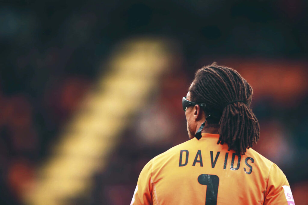 Edgar Davids back view with dreadlocks and sports glasses in orange jersey at stadium wallpaper