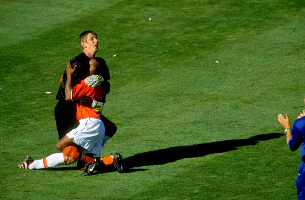 Edgar Davids and Edwin van der Sar celebrate on green football field showing passion and unity Wallpaper