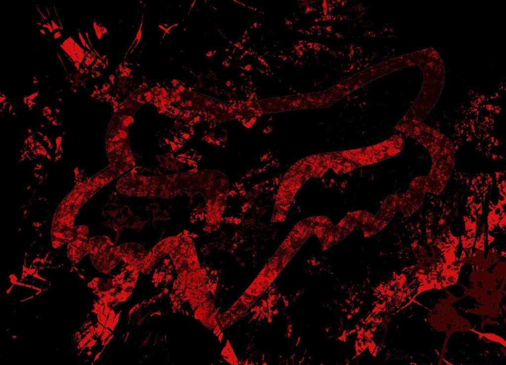 Fox Racing logo wallpaper with bold red paint splatter on black gritty motocross background