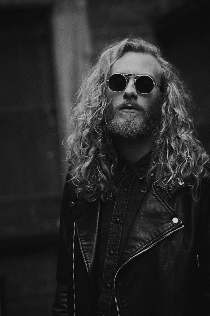 Black and white portrait of bearded man with long wavy hair leather jacket and round sunglasses Wallpaper