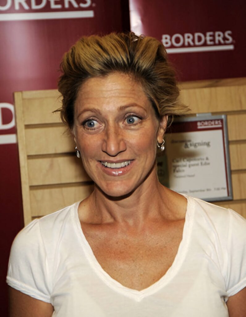 Edie Falco in candid pose with warm red beige background and book displays soft natural lighting Wallpaper
