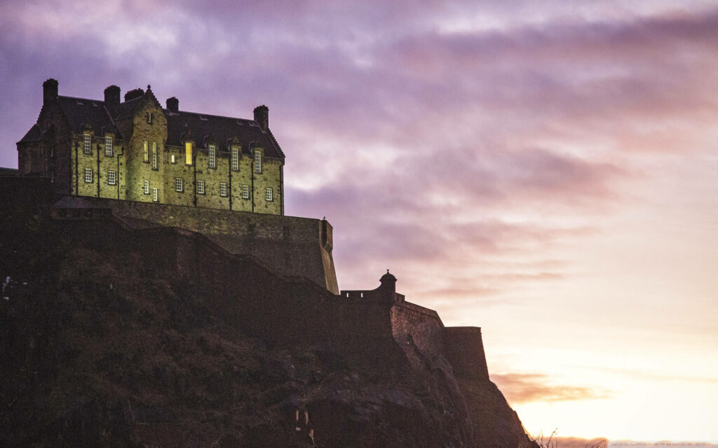 Edinburgh Castle on rugged hill at sunset with purple and gold sky historic Scottish landmark Wallpaper