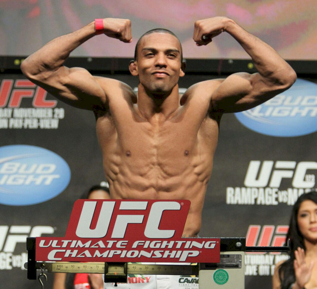 Edson Barboza flexes muscles confidently at UFC weigh-in stage with UFC logo and banners Wallpaper