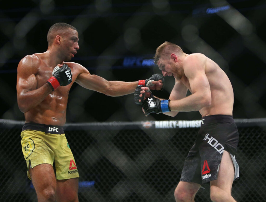 UFC fighters Edson Barboza and Dan Hooker battling intensely inside octagon with bright lights Wallpaper
