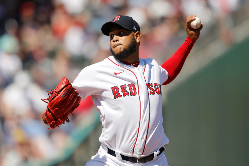 Eduardo Rodríguez pitching for Boston Red Sox with vivid red glove in dynamic action shot Wallpaper