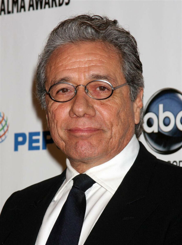 Edward James Olmos in black suit at formal event with logo background confident expression wallpaper