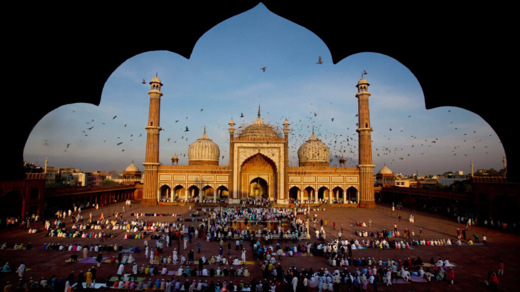 Grand mosque at sunset with golden light worshippers praying Eid celebration wallpaper background