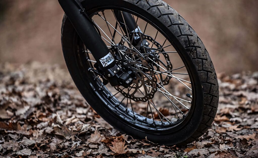 Close-up of electric bike front wheel with thick tread tire and disc brake on autumn leaves Wallpaper