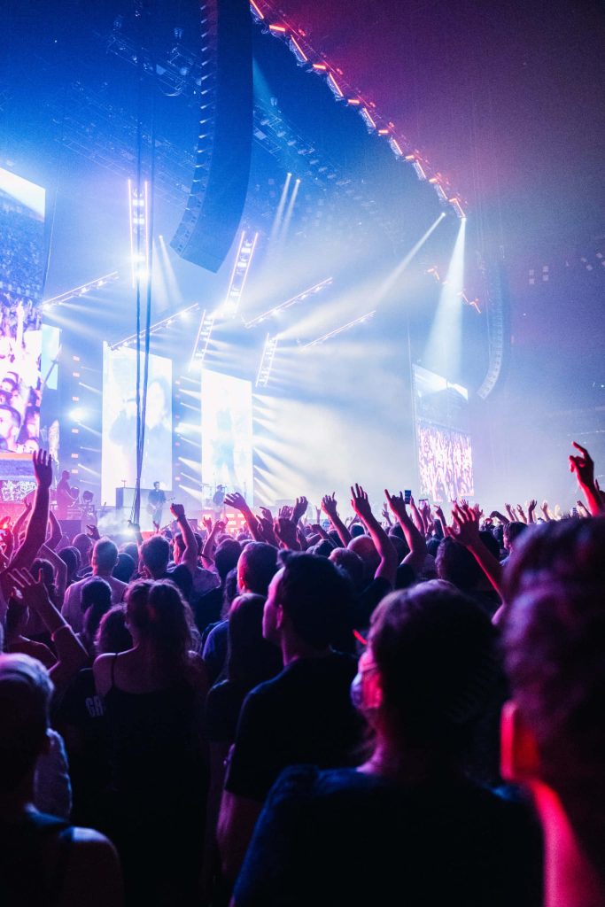 Giant music concert wallpaper with cheering crowd blue stadium lights bright stage spotlights