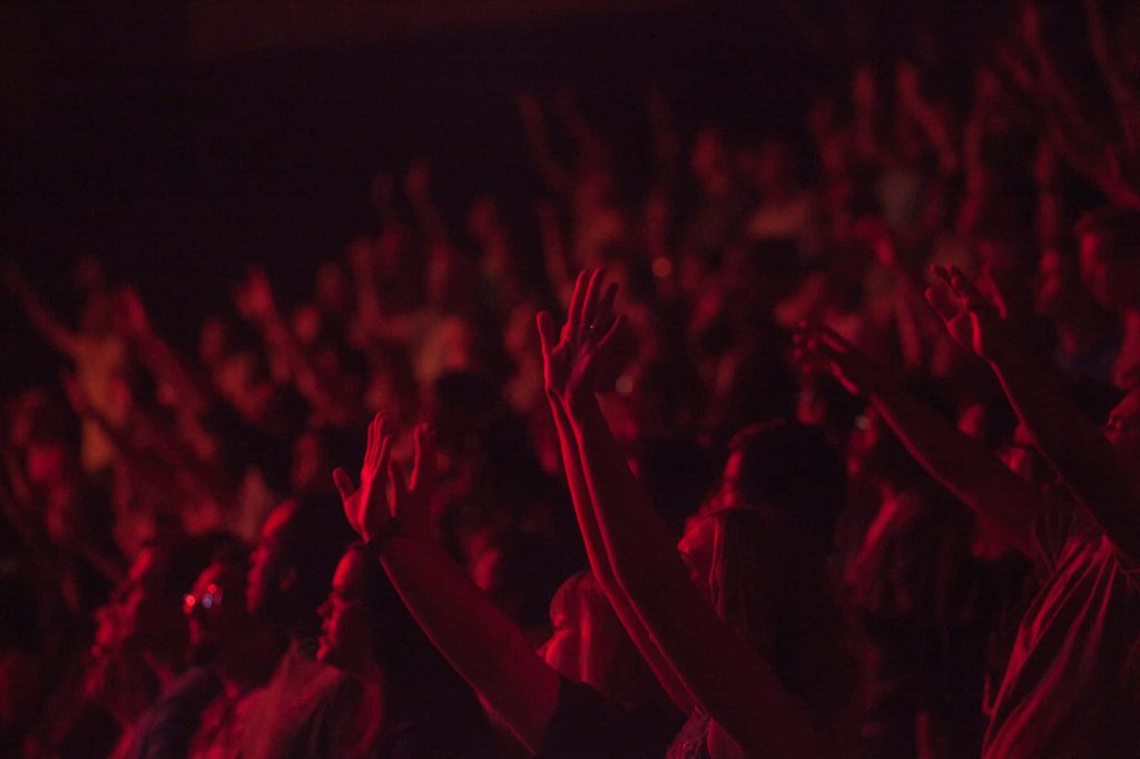 Cheering concert crowd silhouette under red stage lights vibrant live music wallpaper background