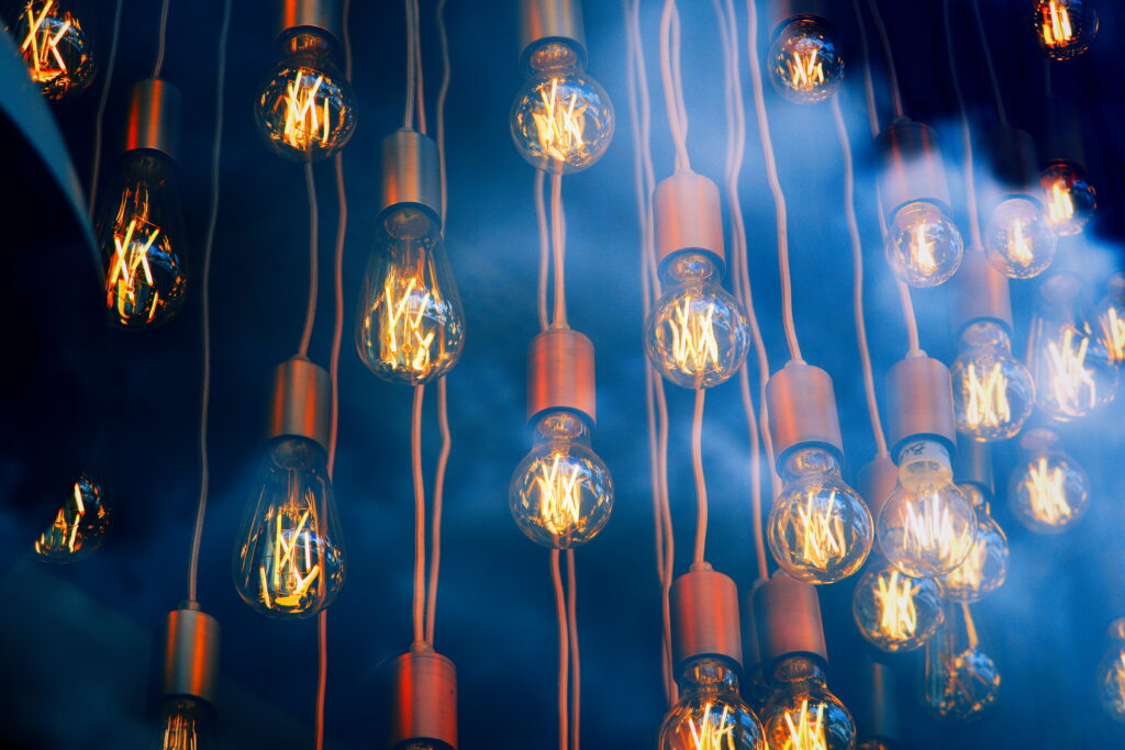 Electric Incandescence: A Mesmerizing Display of Glowing Smoke in a Captivating Light Bulb Ballet Wallpaper