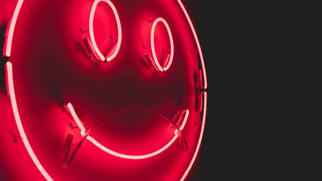 Neon red glowing smiley face on dark background cyberpunk wallpaper for modern devices