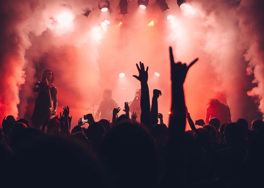 Fans reaching stage amid red spotlights and smoke at electrifying live rock concert background wallpaper