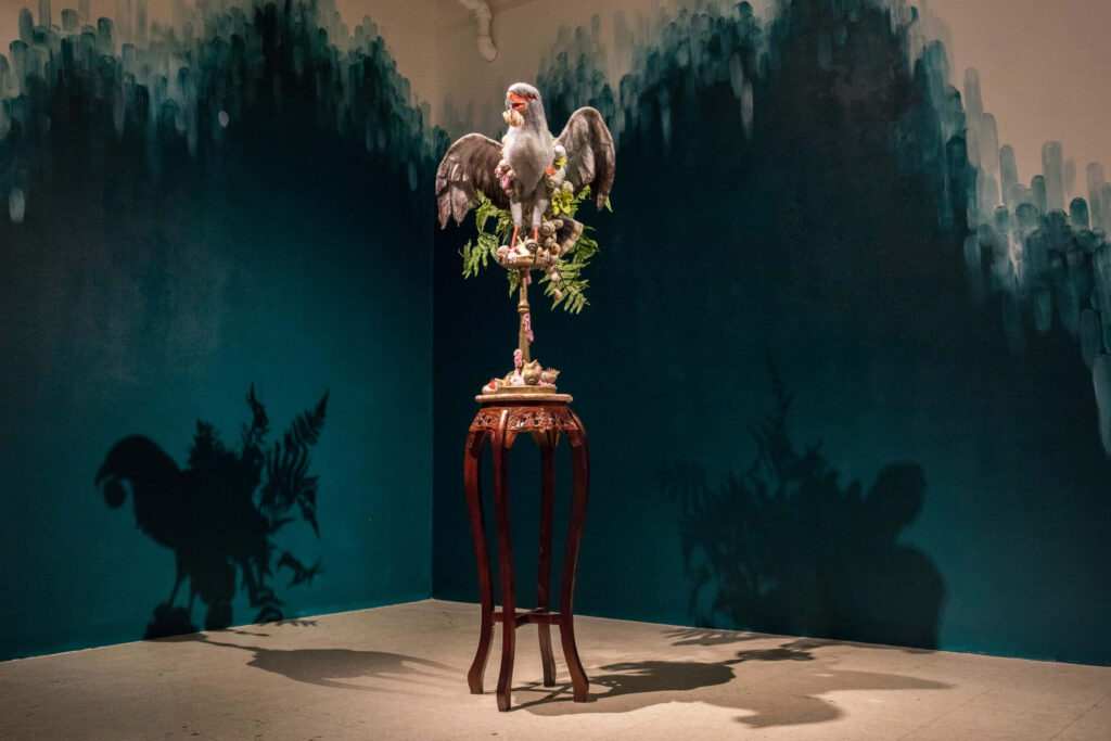 Striking Bird Sculpture with Ornate Stand and Rich Background Wallpaper