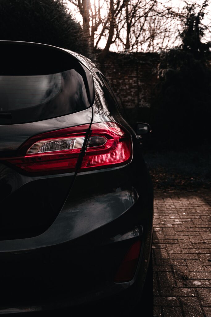 Elegant Black Car Rear View with Dramatic Sky and Tree Silhouettes Wallpaper