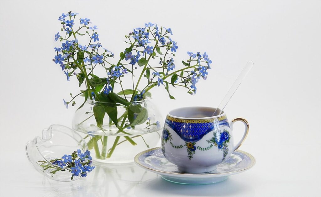 Serene Blue Forget-Me-Nots in Glass Jug with Elegant Teacup Background Wallpaper