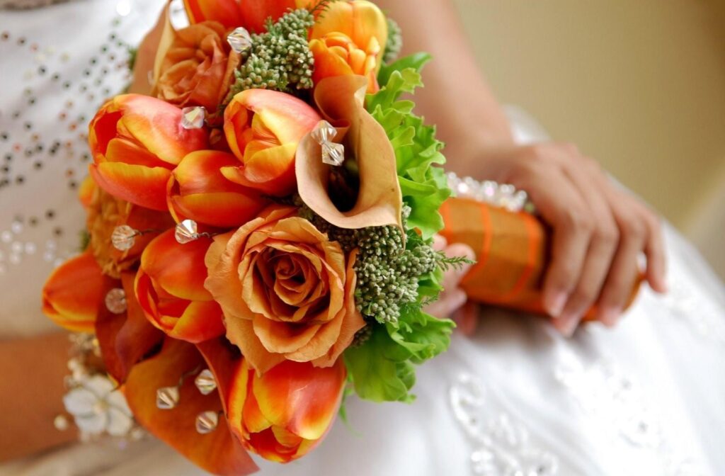 Vibrant Orange Roses & Tulips Bridal Bouquet Against Elegant Gown Wallpaper