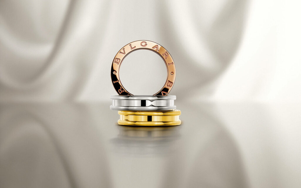 Elegant Bvlgari rose gold white gold yellow gold rings on silky cream background luxury wallpaper