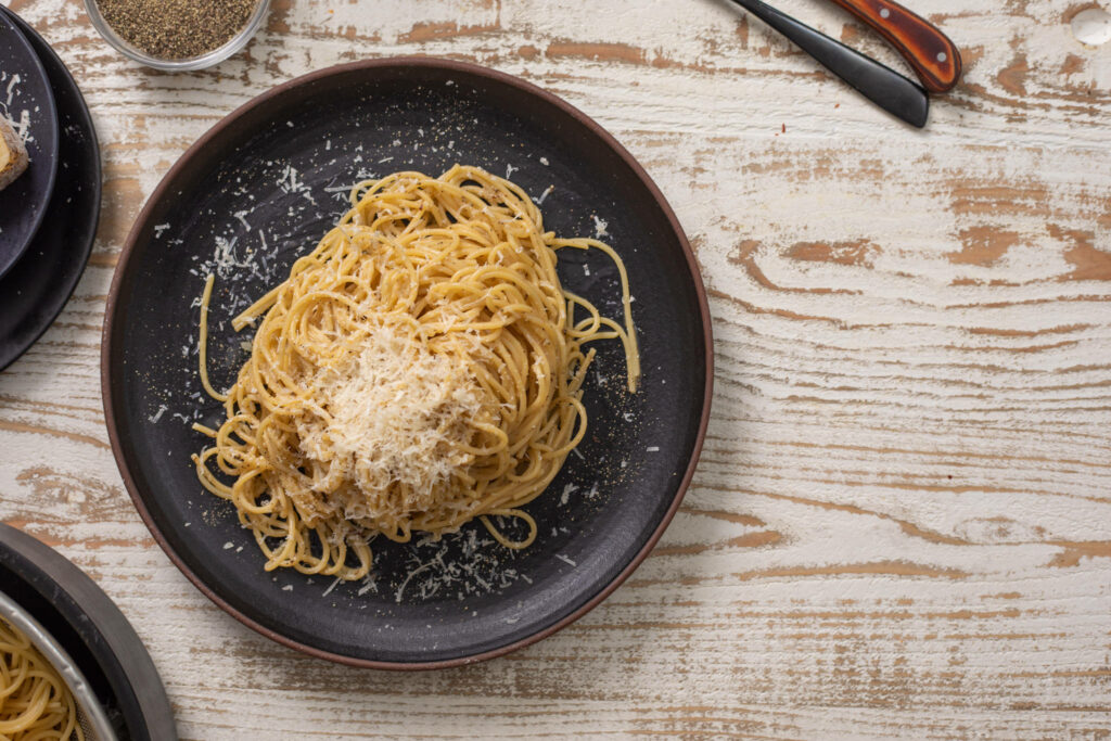 Elegant Cacio e Pepe Dish on Rustic Lava Ware | Textured Wallpaper Background