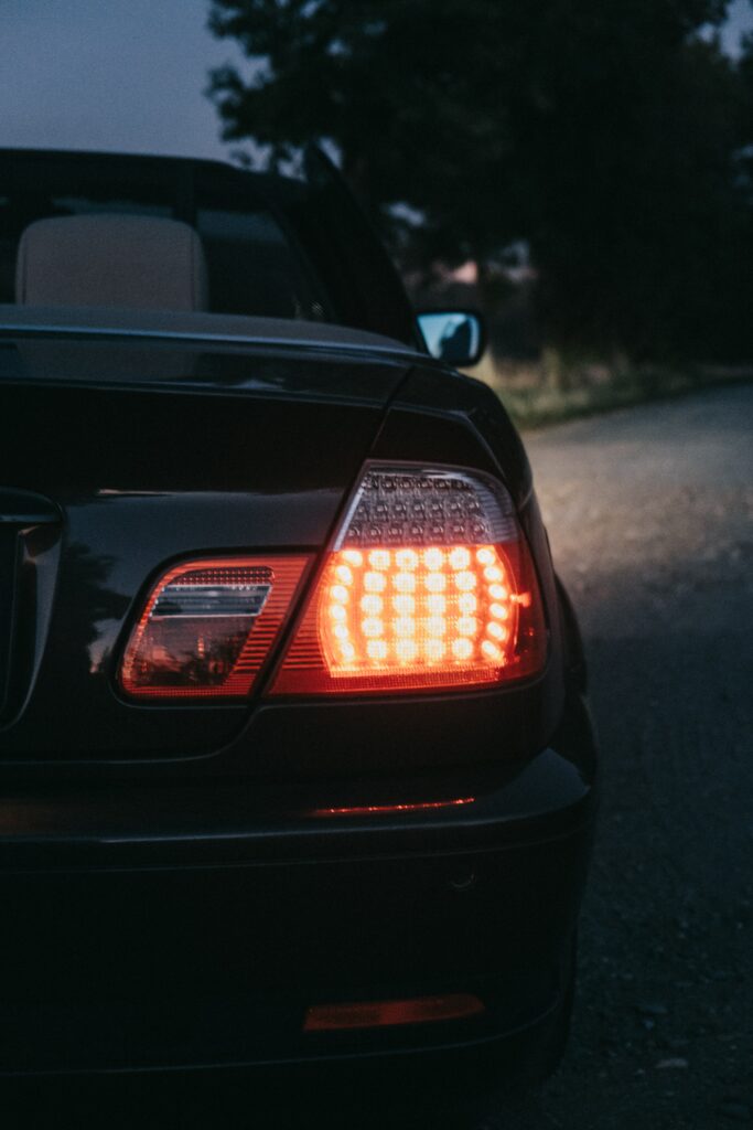 Sleek Car Rear View with Illuminated Taillight on Dimly Lit Road Wallpaper