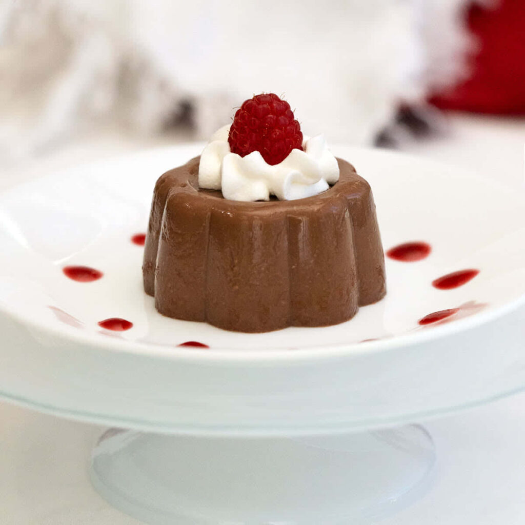 Chocolate blancmange dessert with whipped cream raspberry and red sauce on white plate wallpaper
