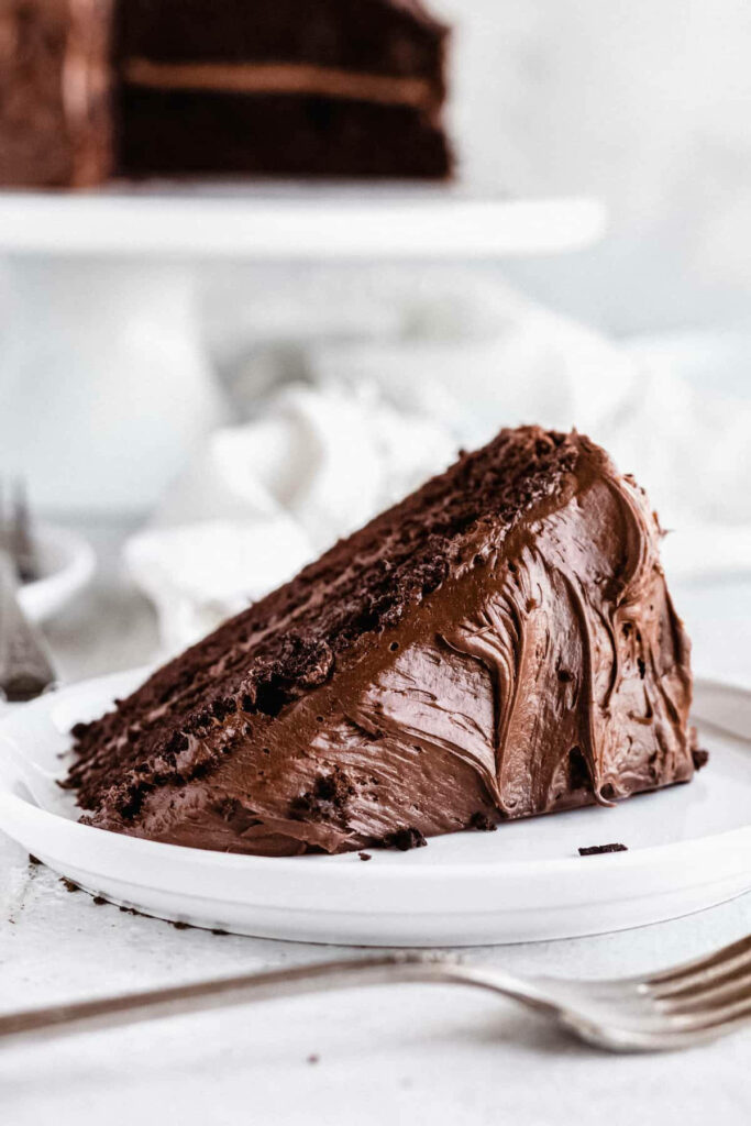 Rich chocolate cake slice with glossy frosting on white background minimalist dessert wallpaper