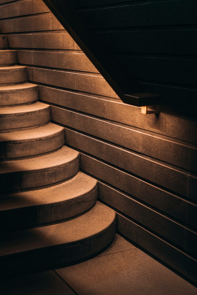 Elegant lighting accentuates sleek concrete staircase against warm backdrop Wallpaper