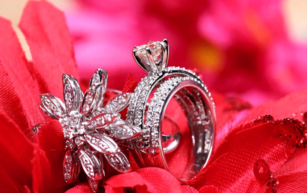 Diamond engagement rings with floral designs on vibrant red petals romantic elegance wallpaper