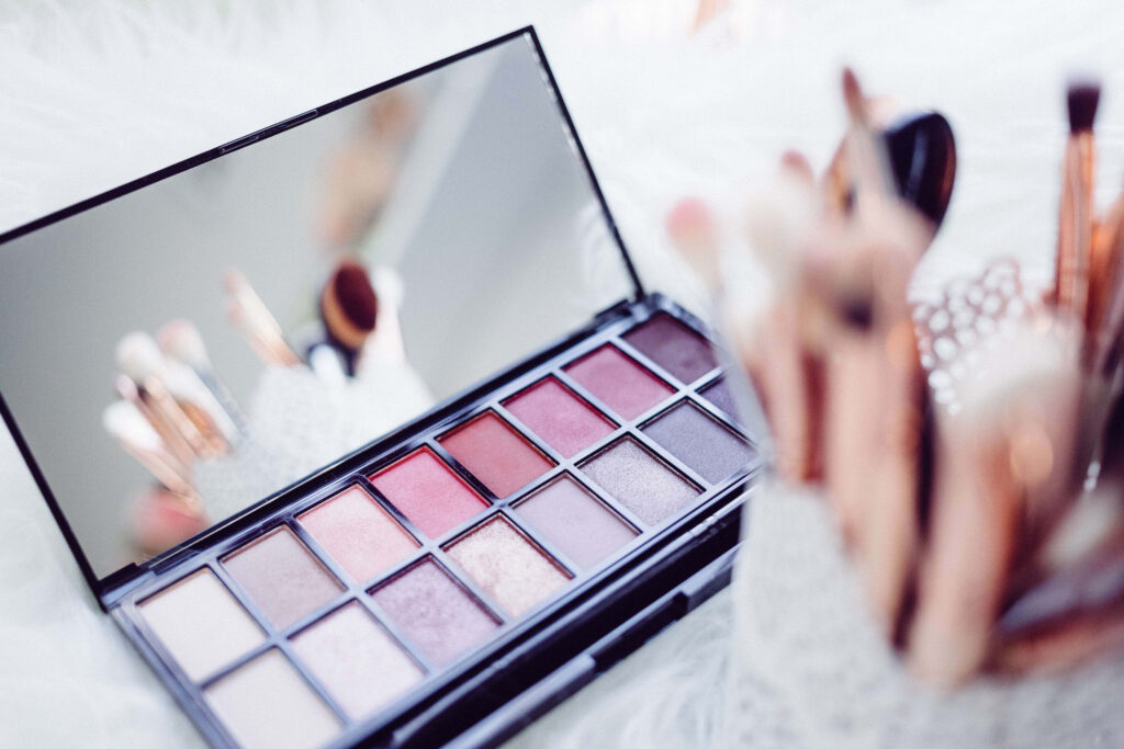 Sleek eyeshadow palette with warm pinks reds nudes and rose gold makeup brushes wallpaper background