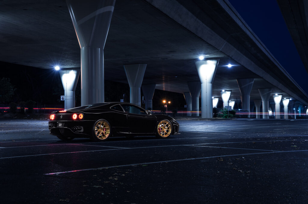 Sleek Black Ferrari 360 Modena at Night: Luxury Under Overpass Wallpaper