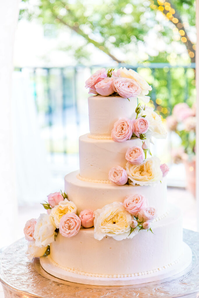 Elegant four-tier wedding cake with pastel roses smooth white icing and romantic floral decor Wallpaper