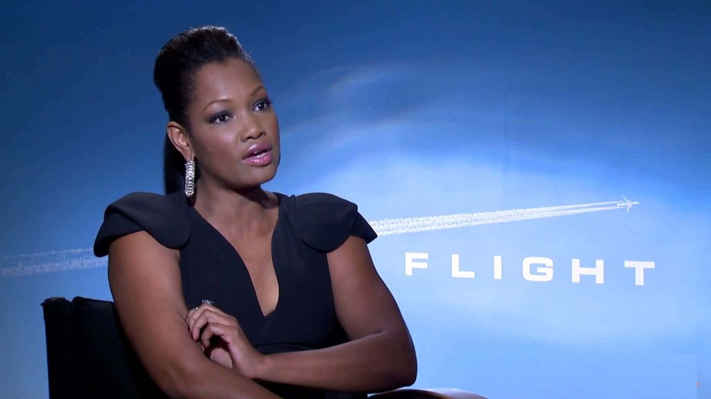 Elegant portrait of Garcelle Beauvais in black outfit at Flight film promo with blue backdrop Wallpaper