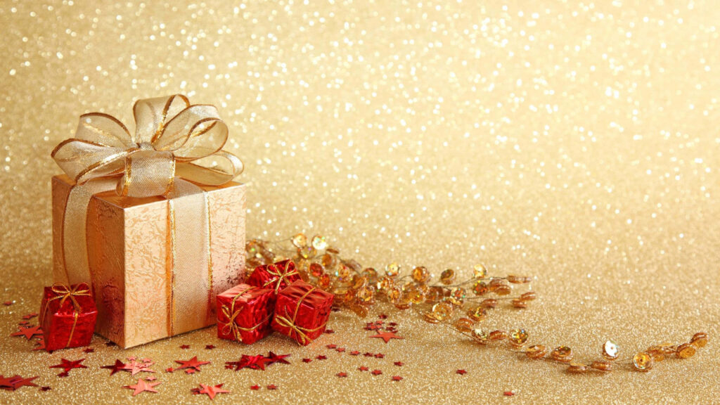 Beautiful gift box with golden ribbon on gold background with red presents and festive confetti Wallpaper