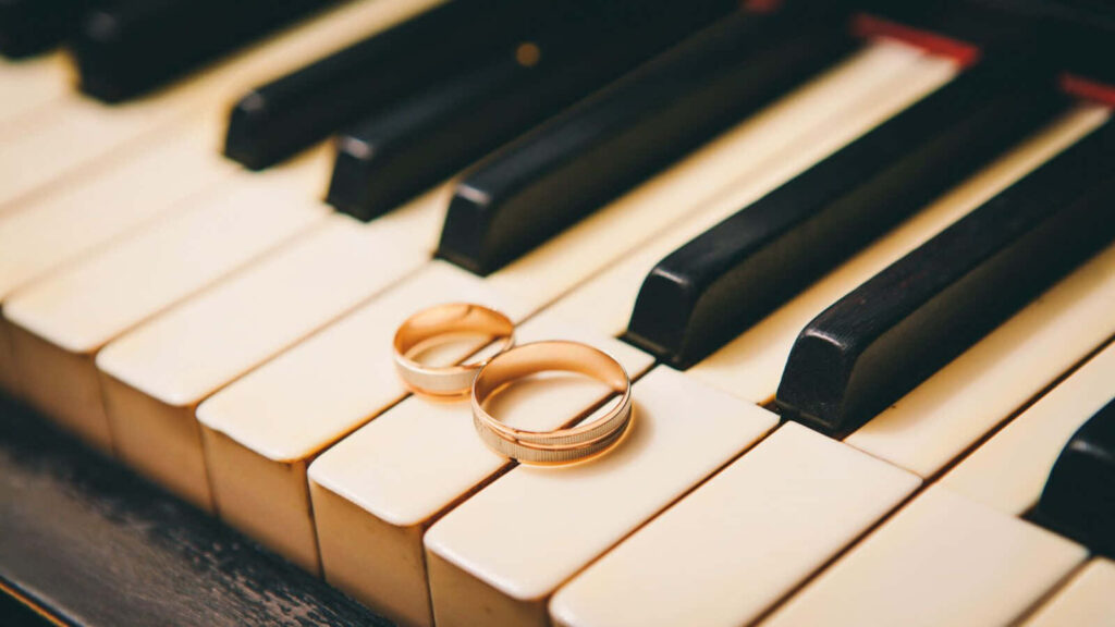 Elegant Gold Rings on Piano Keys - Timeless Music Wallpaper