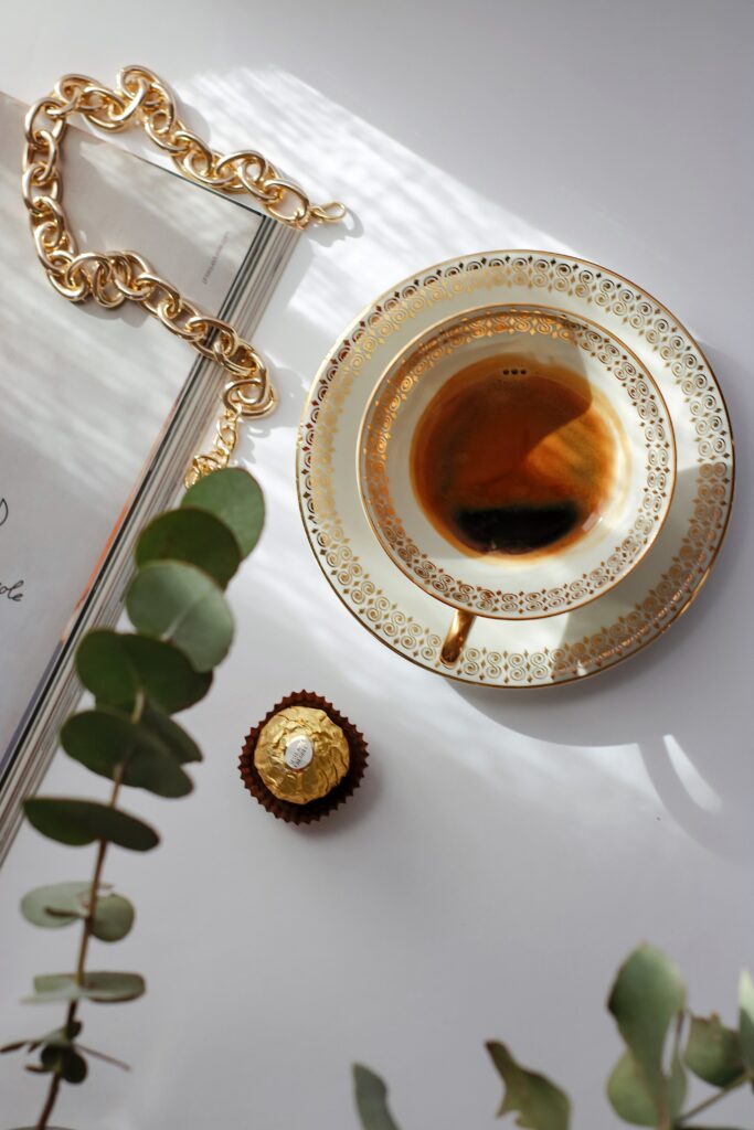 Luxurious Coffee Setup: Gold-Trimmed Cup, Candy & Elegant Decor Wallpaper