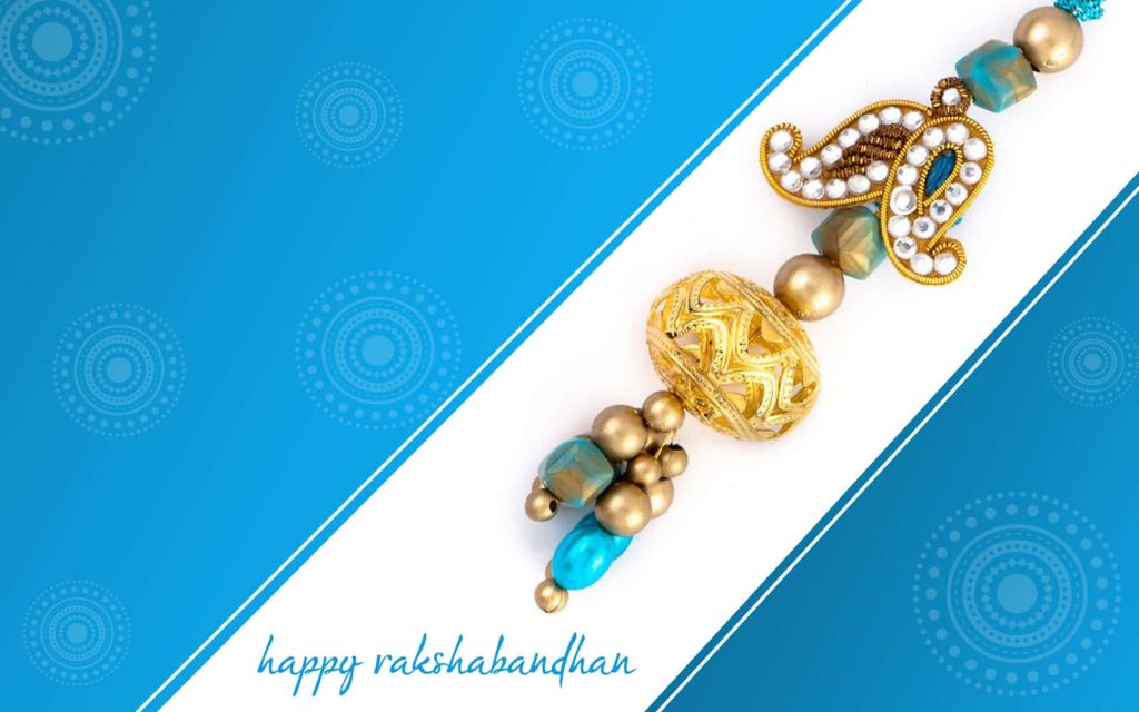 Festive Raksha Bandhan wallpaper with golden paisley Rakhi on blue mandala patterned background
