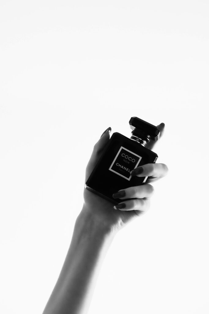 Elegant Hand Holding Coco Chanel Perfume - Luxury Grayscale Wallpaper
