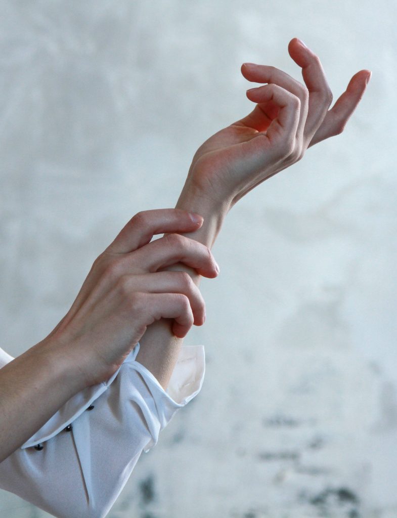 Elegant hand model in artistic pose with white shirt on neutral textured minimalist background Wallpaper