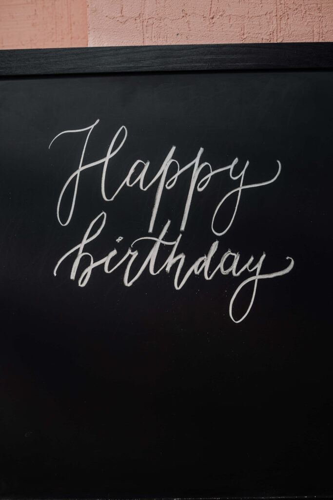 Happy birthday message in elegant white script on black chalkboard background wallpaper